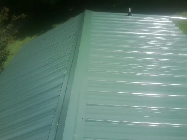 New green metal panels meeting at the ridge of a roof in Altoona